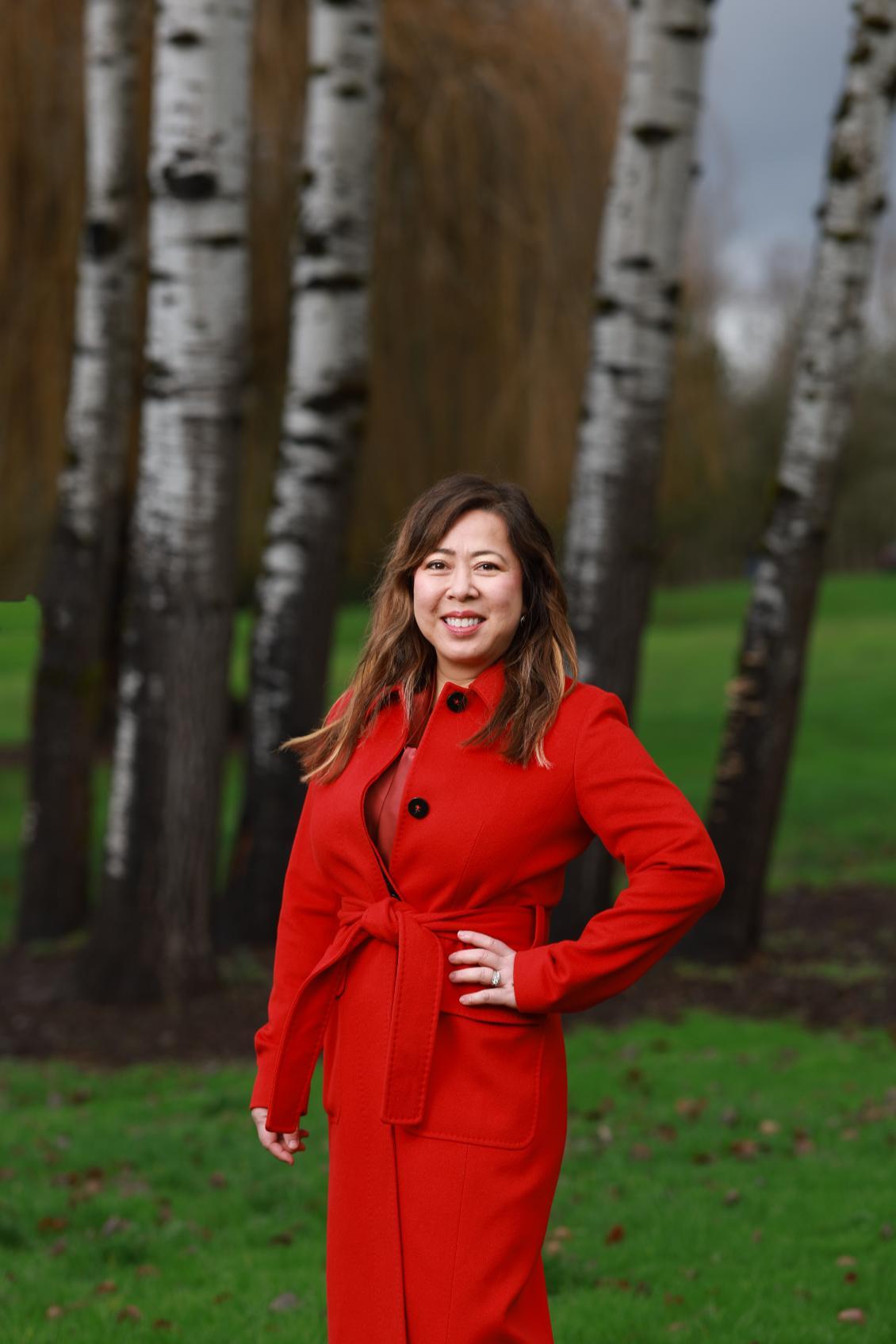 Madeline Haydon standing in front of trees in red coat