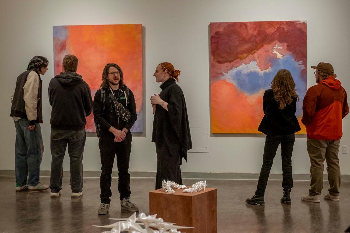 Students standing in front of artwork at the 2025 Studio Arts Exhibition opening reception.