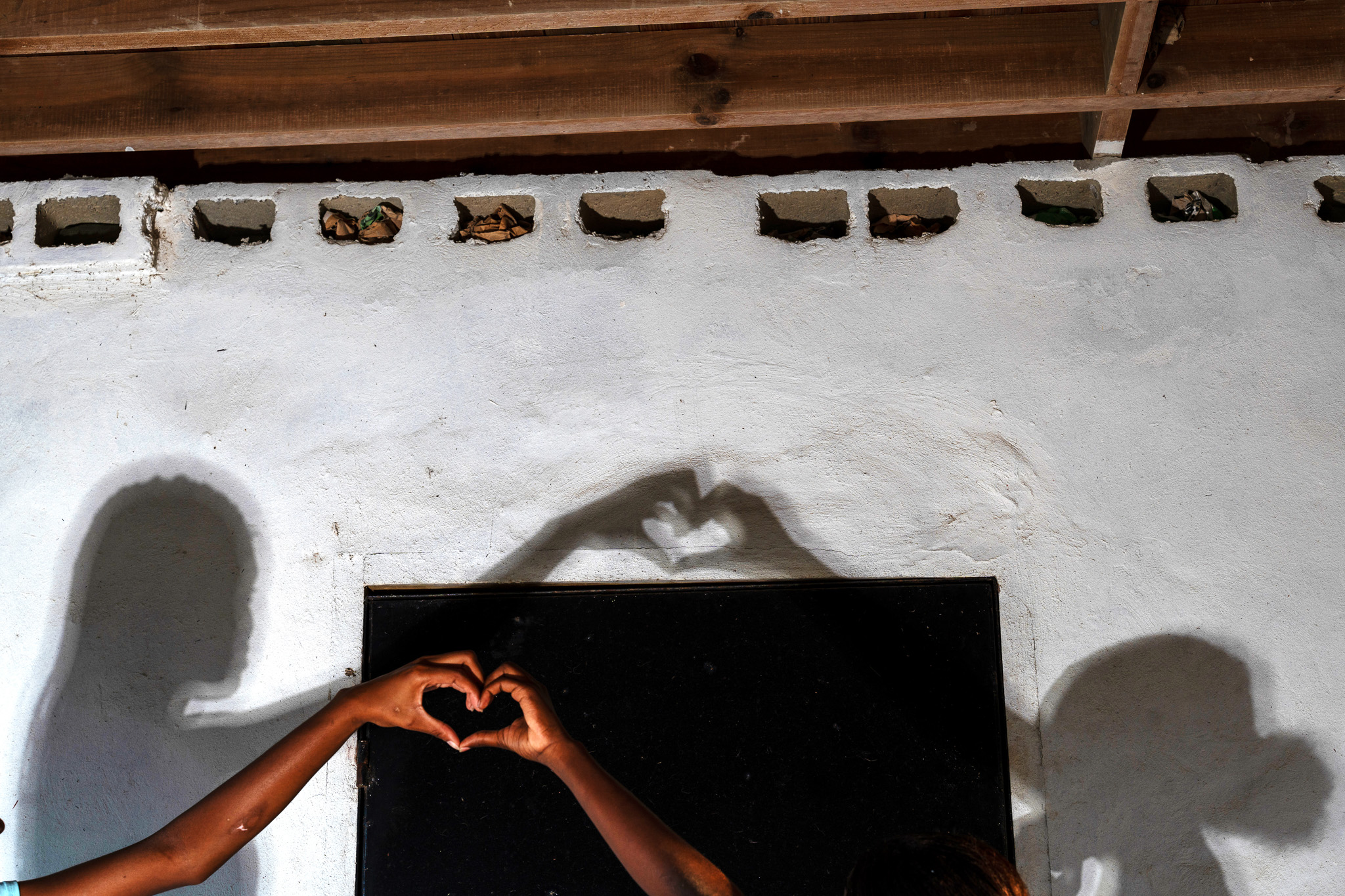 Two people extending one hand each, meeting in the middle, to form a heart with their hands