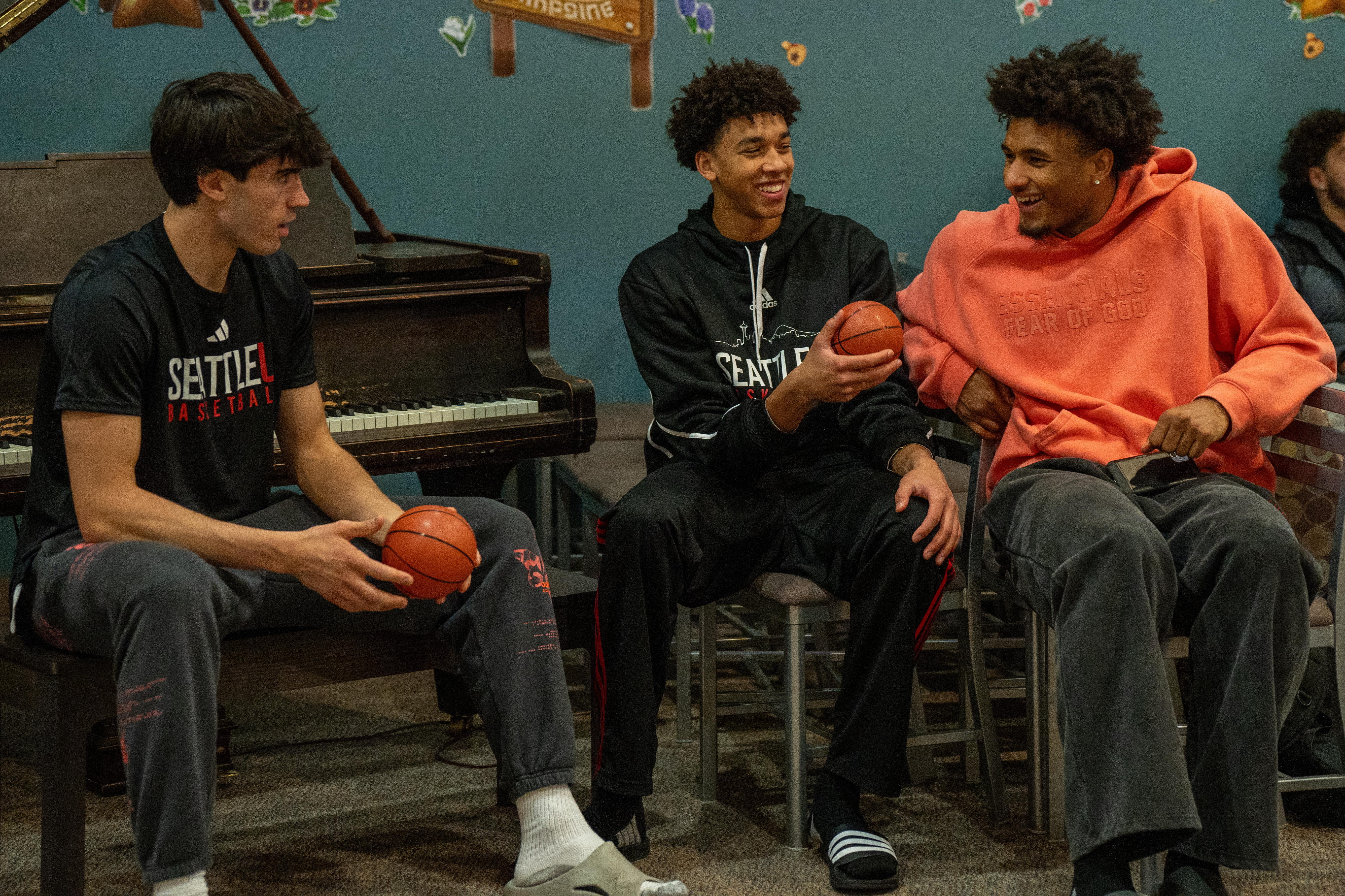 Three students sitting while holding mini basketballs