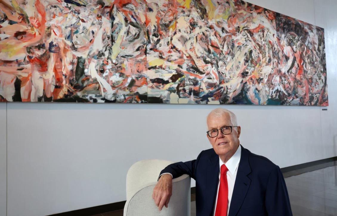 Richard Hedreen sits in front of a piece of art